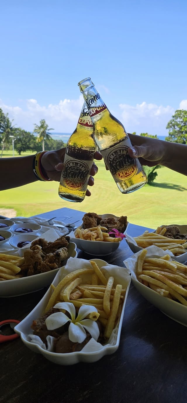 Vailima beers raised above a table overlooking Faleata Golf Course